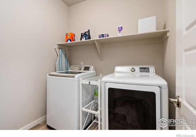 clothes washing area with baseboards, laundry area, wood finished floors, and washer and dryer