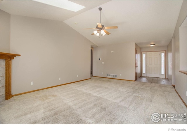 unfurnished living room with vaulted ceiling with skylight, carpet flooring, visible vents, and baseboards