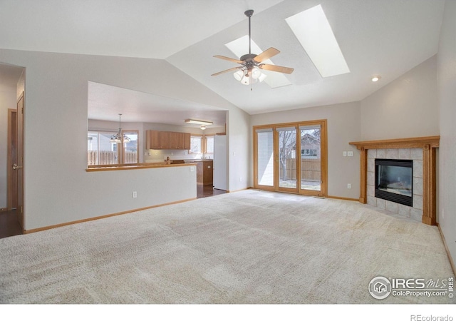 unfurnished living room with lofted ceiling with skylight, carpet, baseboards, and a tiled fireplace