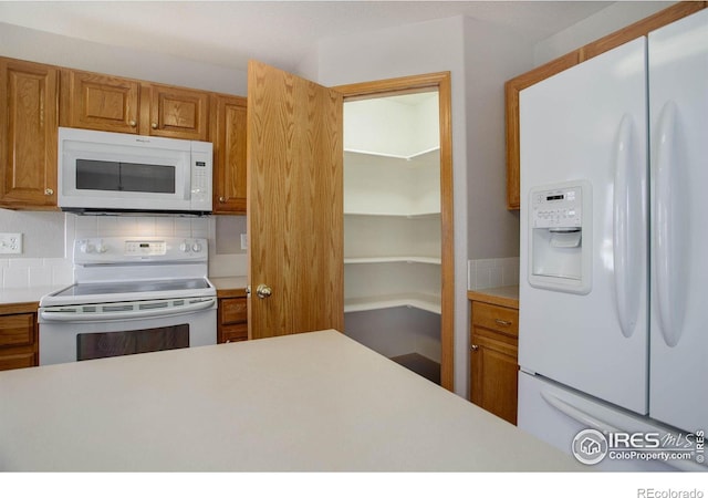 kitchen with brown cabinets, white appliances, light countertops, and backsplash