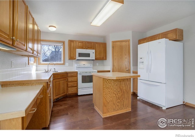 kitchen featuring white appliances, dark wood finished floors, a kitchen island, light countertops, and a sink