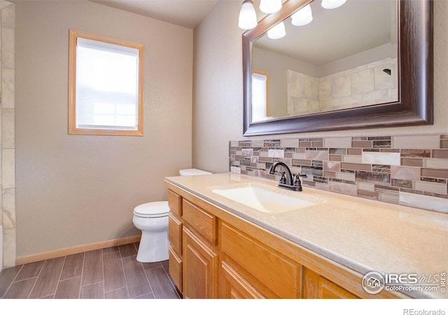 bathroom featuring wood finish floors, tasteful backsplash, toilet, vanity, and baseboards