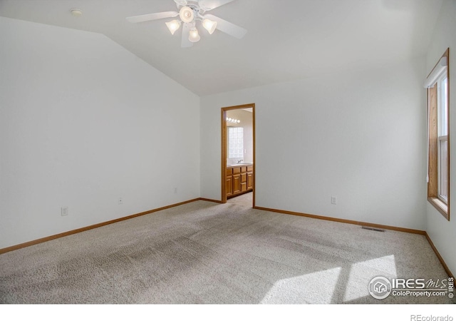 spare room featuring light carpet, vaulted ceiling, visible vents, and baseboards