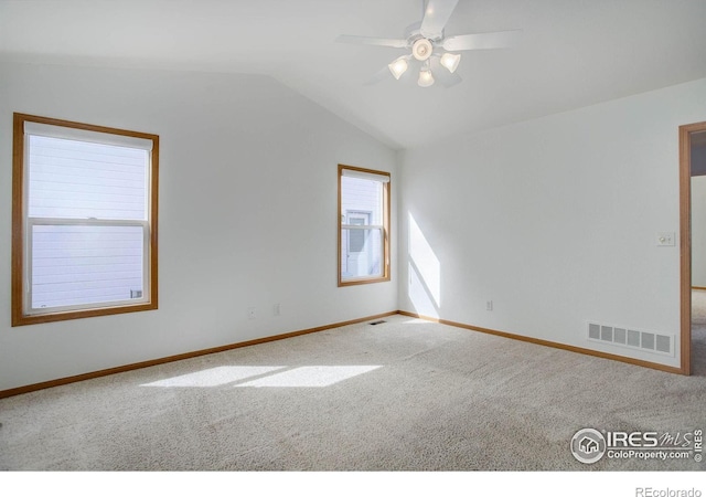 carpeted empty room with lofted ceiling, baseboards, visible vents, and a ceiling fan