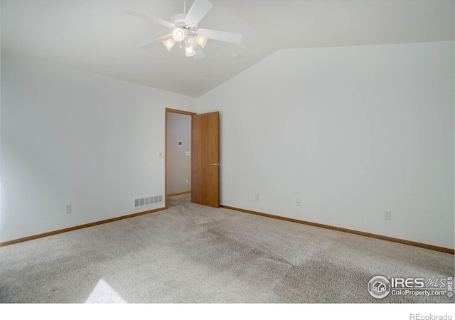 empty room with carpet, lofted ceiling, visible vents, a ceiling fan, and baseboards