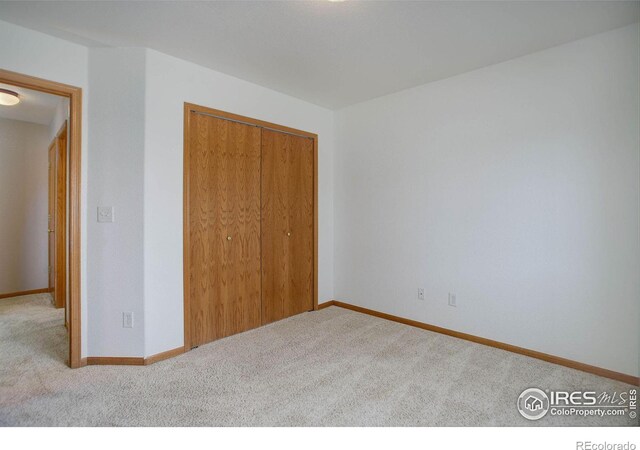 unfurnished bedroom featuring a closet, baseboards, and carpet flooring