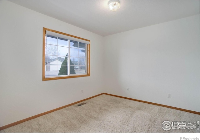 spare room featuring carpet, visible vents, and baseboards