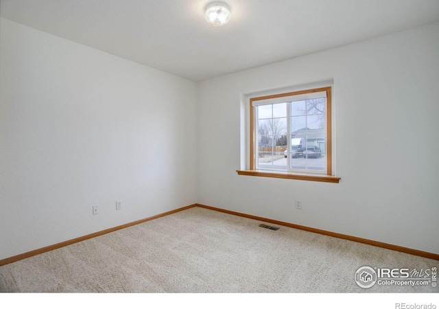 carpeted spare room with visible vents and baseboards