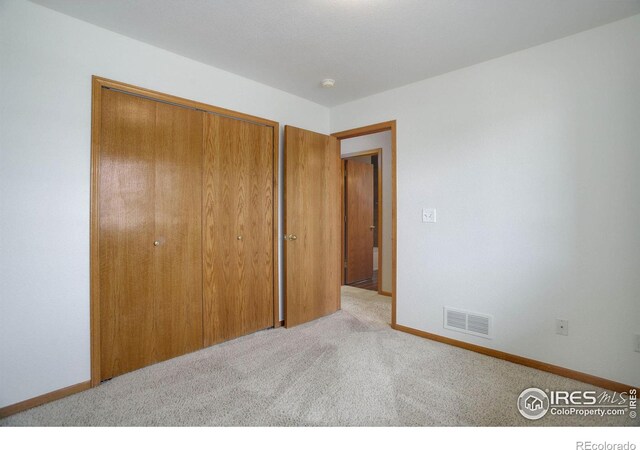 unfurnished bedroom featuring carpet floors, a closet, visible vents, and baseboards