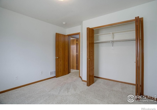 unfurnished bedroom with baseboards, a closet, visible vents, and carpet flooring