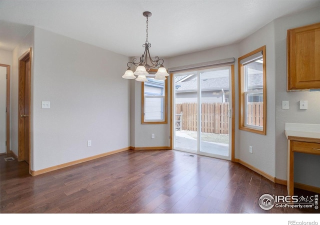 unfurnished dining area featuring baseboards, visible vents, a chandelier, and dark wood finished floors