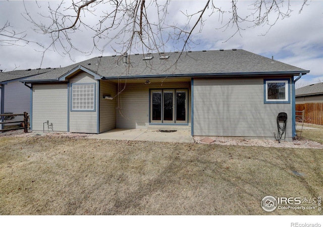 back of house with a shingled roof, fence, a lawn, and a patio