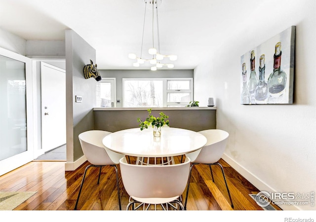 dining room with an inviting chandelier, baseboards, and wood-type flooring