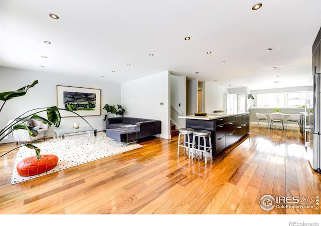 kitchen with a center island, open floor plan, a kitchen bar, light wood-type flooring, and light countertops