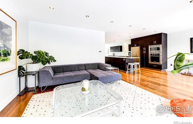 living area featuring recessed lighting, light wood-type flooring, and baseboards