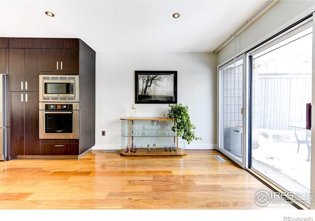 kitchen with dark brown cabinetry, light wood-style floors, visible vents, and appliances with stainless steel finishes