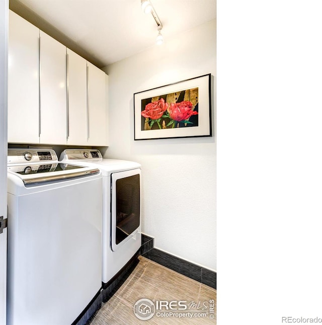 laundry room with cabinet space, track lighting, independent washer and dryer, and baseboards