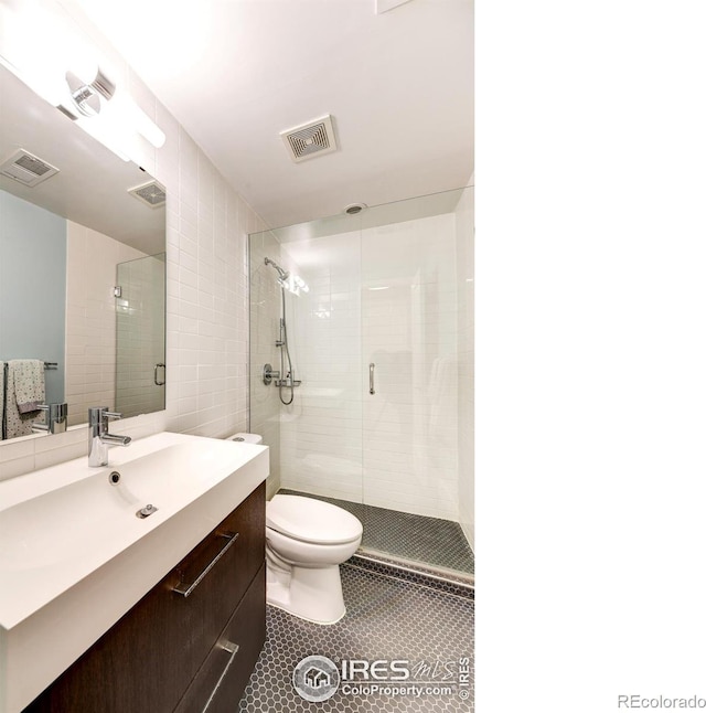 full bathroom featuring vanity, a shower stall, toilet, and visible vents