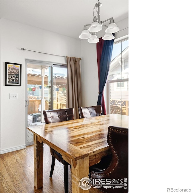 dining room with wood finished floors, a notable chandelier, and baseboards