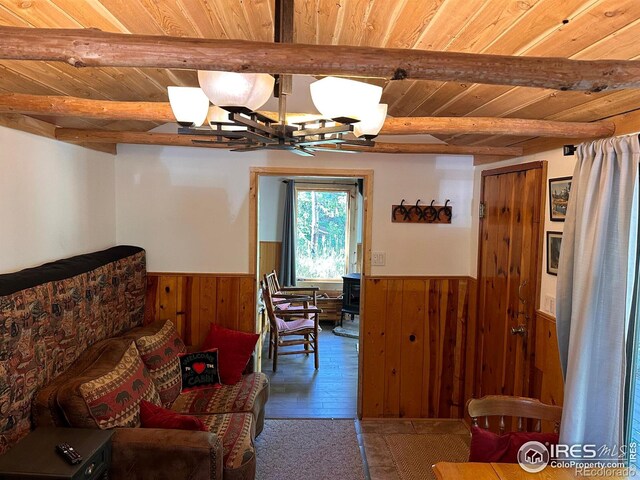 living area with a wainscoted wall, beam ceiling, and wood ceiling