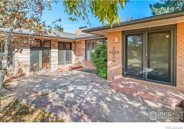 back of property featuring brick siding and a patio area