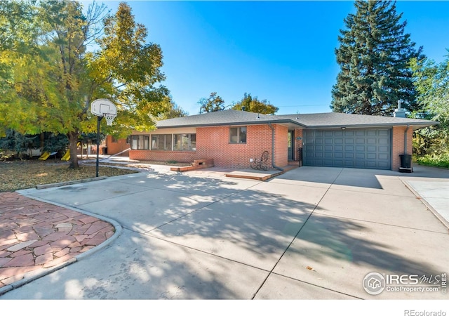 ranch-style house featuring a garage, concrete driveway, and brick siding