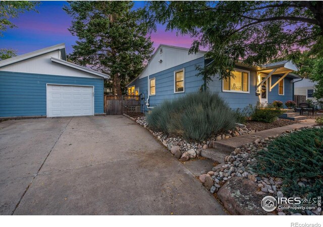 view of side of property with concrete driveway, fence, and an attached garage