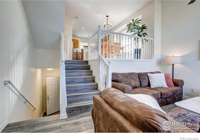 living area with light wood-style floors, recessed lighting, an inviting chandelier, and stairs