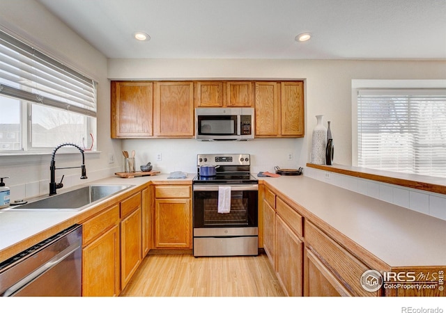 kitchen featuring a wealth of natural light, appliances with stainless steel finishes, light wood-style floors, and a sink