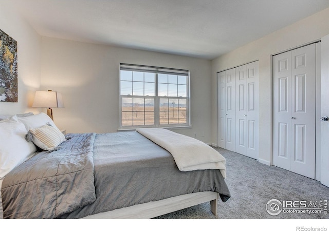 bedroom featuring two closets, baseboards, and carpet flooring