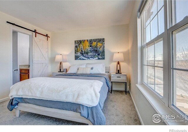 carpeted bedroom featuring a barn door and baseboards