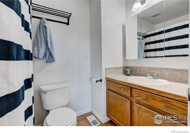 full bathroom with baseboards, visible vents, vanity, and toilet