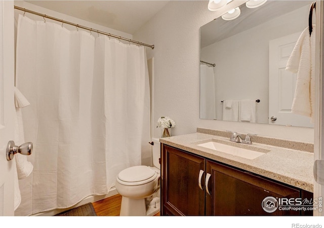 bathroom featuring curtained shower, vanity, toilet, and wood finished floors