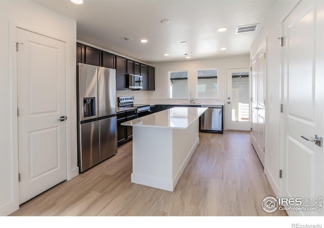 3282 Crusader St, Fort Collins, CO 80524 - kitchen featuring appliances with stainless steel finishes, a sink, light wood finished floors, a kitchen island, and recessed lighting