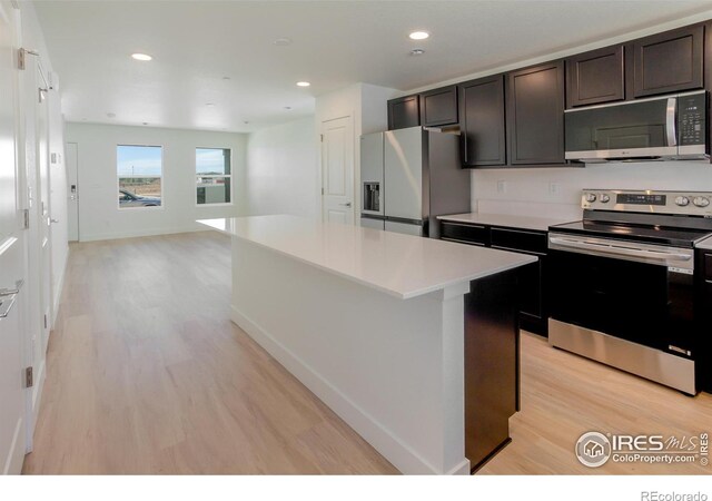 3282 Crusader St, Fort Collins, CO 80524 - kitchen featuring stainless steel appliances, light wood-style flooring, a center island, light countertops, and open floor plan