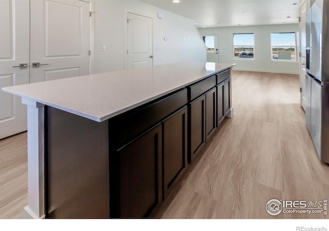 3282 Crusader St, Fort Collins, CO 80524 - kitchen with light wood finished floors, a kitchen island, recessed lighting, stainless steel fridge, and open floor plan