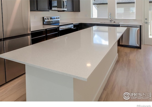 3282 Crusader St, Fort Collins, CO 80524 - kitchen featuring stainless steel appliances, a sink, light wood finished floors, and a kitchen island