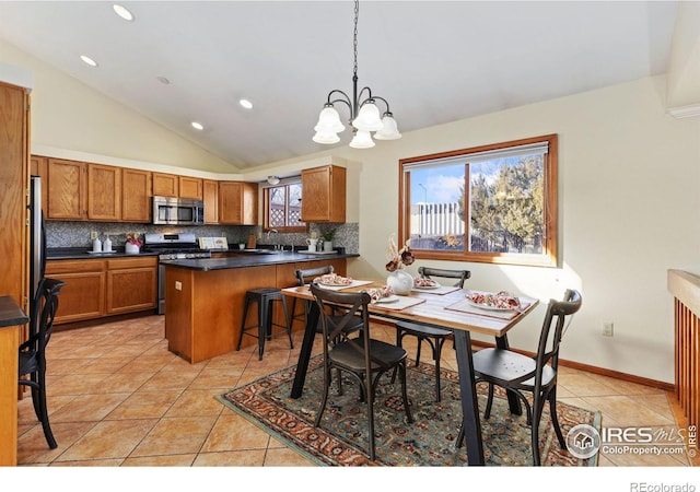 kitchen featuring lofted ceiling, decorative backsplash, appliances with stainless steel finishes, brown cabinetry, and a peninsula