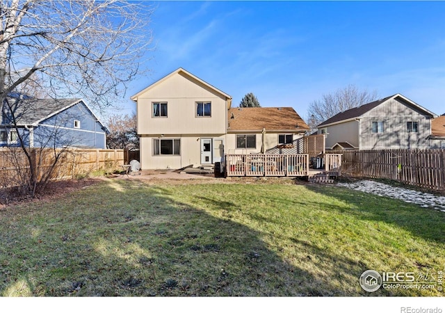 rear view of house featuring a fenced backyard, a deck, and a yard