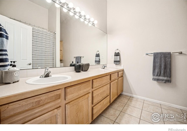 full bath featuring double vanity, tile patterned flooring, a sink, and baseboards