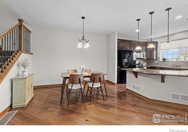 dining space featuring stairway, visible vents, and dark wood finished floors