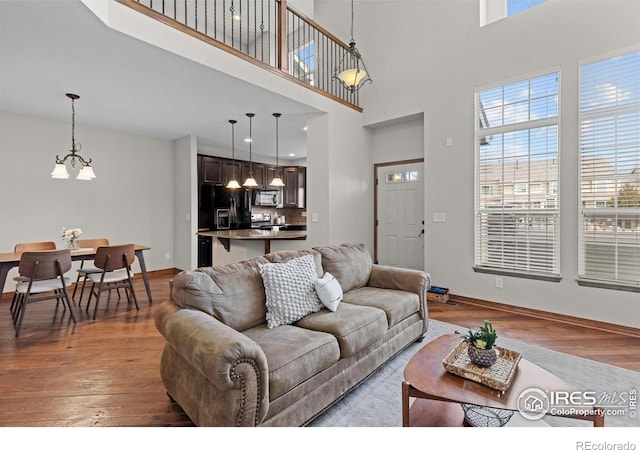 living area featuring baseboards, a chandelier, and wood finished floors