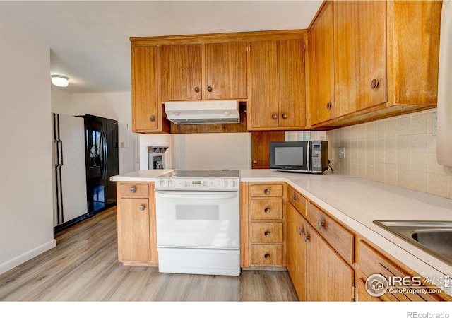 kitchen with electric range, black fridge with ice dispenser, light wood-style flooring, light countertops, and under cabinet range hood