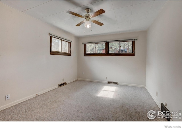 carpeted empty room featuring a ceiling fan, visible vents, and baseboards