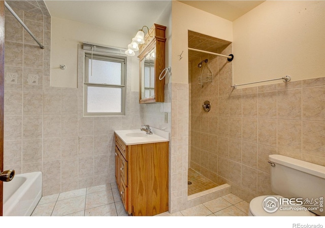 bathroom with toilet, tile patterned flooring, a tile shower, and tile walls