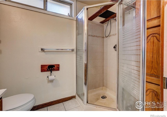 bathroom with a stall shower, tile patterned flooring, toilet, and baseboards