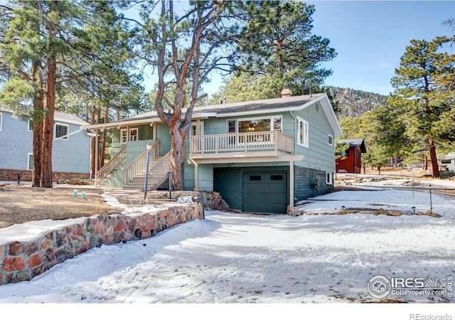 view of front of home featuring covered porch, stairway, a chimney, and an attached garage