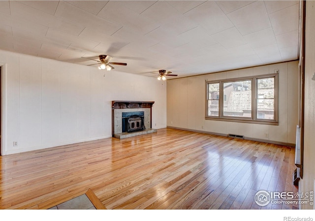 unfurnished living room with a fireplace with raised hearth, light wood finished floors, and visible vents