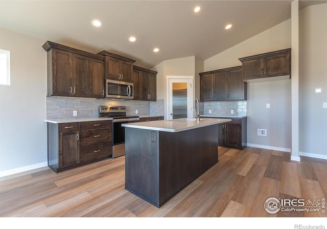 kitchen featuring light wood-style flooring, stainless steel appliances, vaulted ceiling, dark brown cabinets, and light countertops