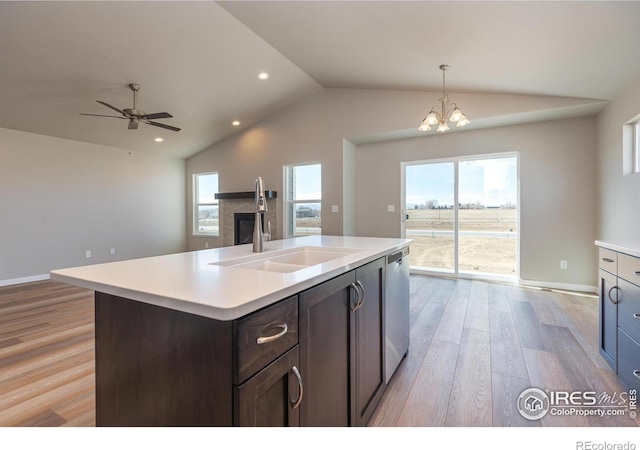 kitchen featuring lofted ceiling, light countertops, light wood-style flooring, stainless steel dishwasher, and a sink